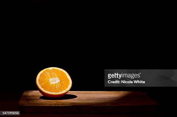 orange in spotlight - dark table stock pictures, royalty-free photos & images