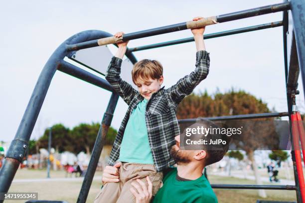 vater hilft seinem sohn beim klimmzug - boys in pullups stock-fotos und bilder