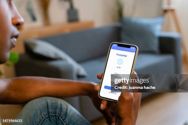 side view of crop anonymous man sitting on sofa and sending money with smartphone while resting in cozy living room at home - conservative members of parliament april 2005 stockfoto's en -beelden