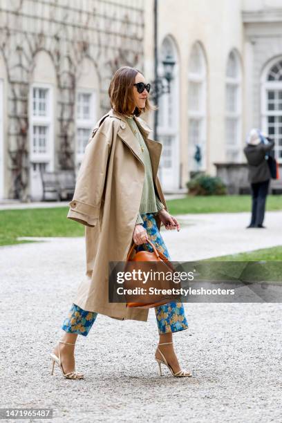 Influencer and style icon Annette Weber, wearing a green pullover by Loro Piana, blue-yellow colored pants by Baum & Pferdgarten, a beige trench coat...