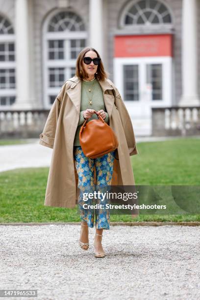 Influencer and style icon Annette Weber, wearing a green pullover by Loro Piana, blue-yellow colored pants by Baum & Pferdgarten, a beige trench coat...