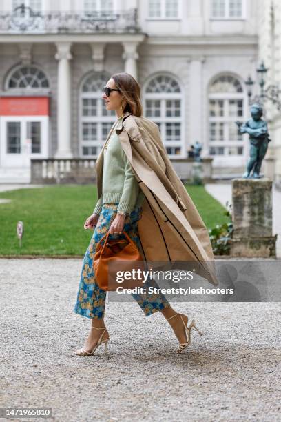 Influencer and style icon Annette Weber, wearing a green pullover by Loro Piana, blue-yellow colored pants by Baum & Pferdgarten, a beige trench coat...