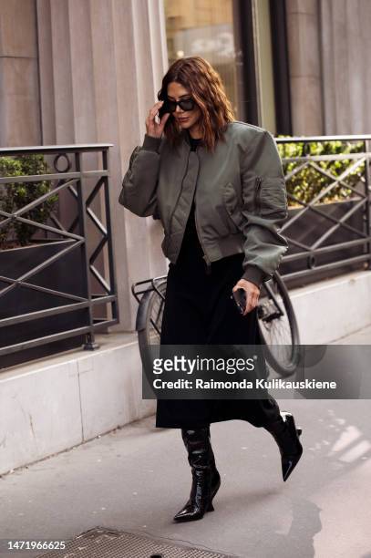 Christine Centenera wears green bomber jacket, black skirt, varnished boots outside the The Row show during Paris Fashion Week - Womenswear Fall...