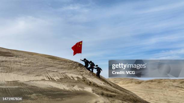 Policemen holding a Chinese national flag patrol the desert area on March 7, 2023 in Altay Prefecture, Xinjiang Uygur Autonomous Region of China.