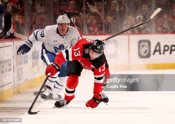 Nico Hischier of the New Jersey Devils takes the puck from Sam Lafferty of the Toronto Maple Leafs during the second period at Prudential Center on...