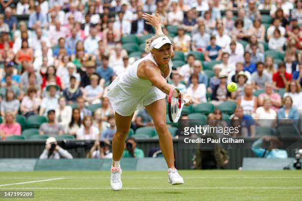 Caroline Wozniacki of Denmark stretches and hits a forehand return during her Ladies' singles first round match against Tamira Paszek of Austria on...
