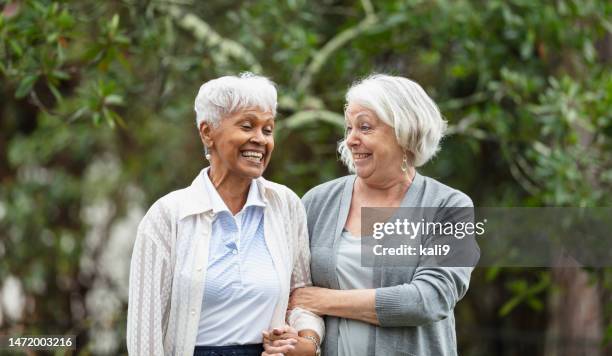 senior women walking, talking in back yard, smiling - mulheres idosas imagens e fotografias de stock