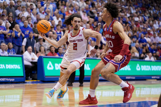Pop Isaacs of the Texas Tech Red Raiders drives to the basket against Jalen Wilson of the Kansas Jayhawks in the first second at Allen Fieldhouse on...