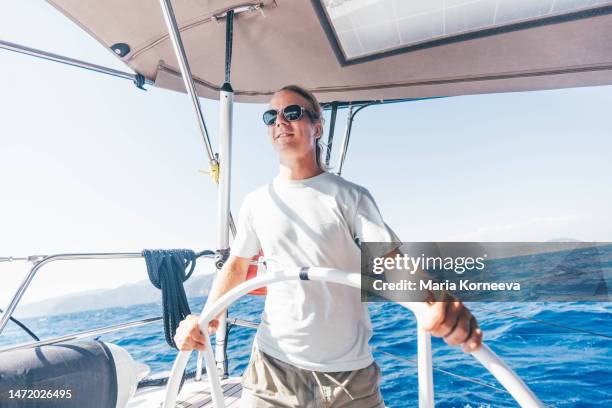 man driving a yacht. - boat steering wheel stock pictures, royalty-free photos & images