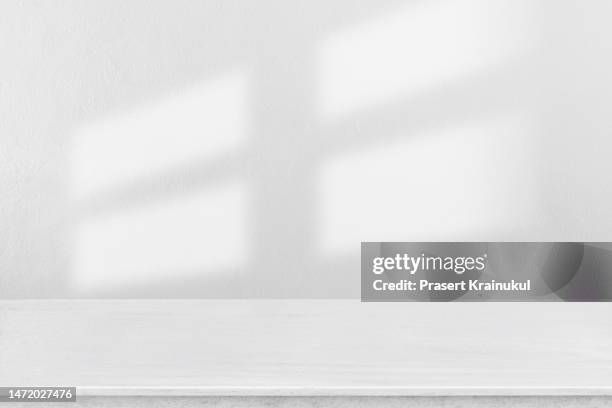 shadow on a white concrete walls on table. - white table stock-fotos und bilder