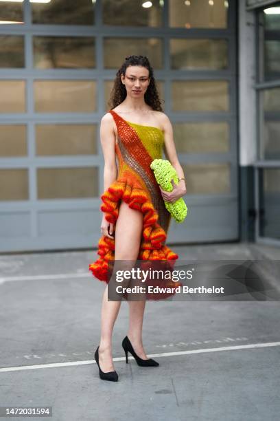 Guest wears a green / orange / gray striped print pattern braided wool ruffled asymmetric knees dress, a neon green braided puffy handbag, black...