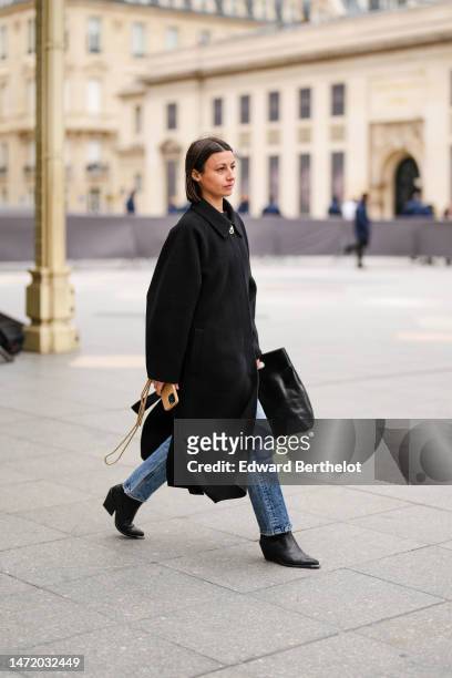 Guest wears a black wool long coat, blue denim pants, a black shiny leather large handbag, black shiny leather block heels / pointed western ankle...