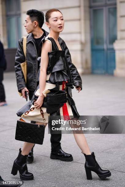 Guest wears a white matte leather and black shiny varnished leather bicolored ruffled pattern sleeveless short dress from Louis Vuitton, a black...