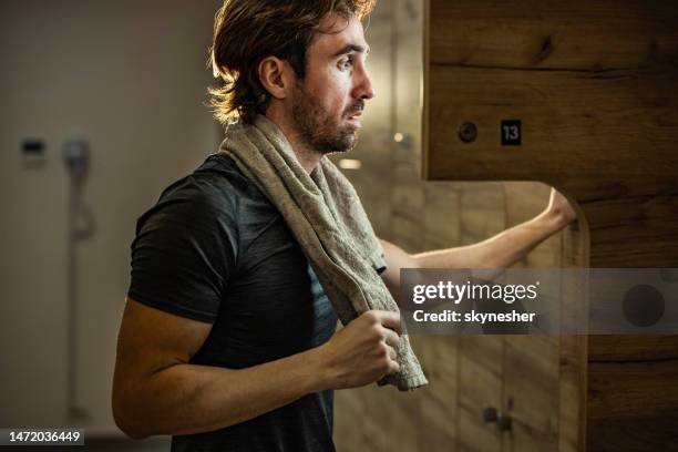 young athletic man taking out his clothes from a locker in a gym's dressing room. - boudoir stockfoto's en -beelden