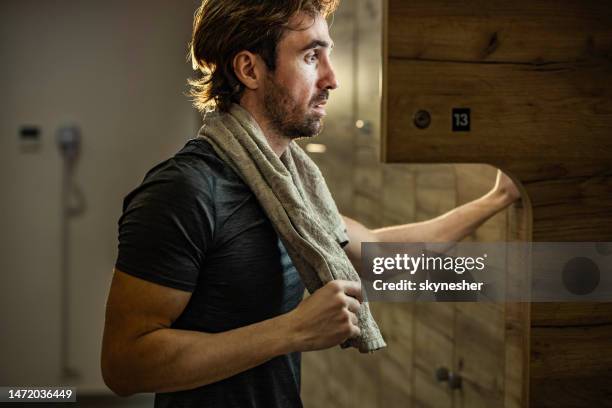 young athletic man taking out his clothes from a locker in a gym's dressing room. - omklädningsrum bildbanksfoton och bilder