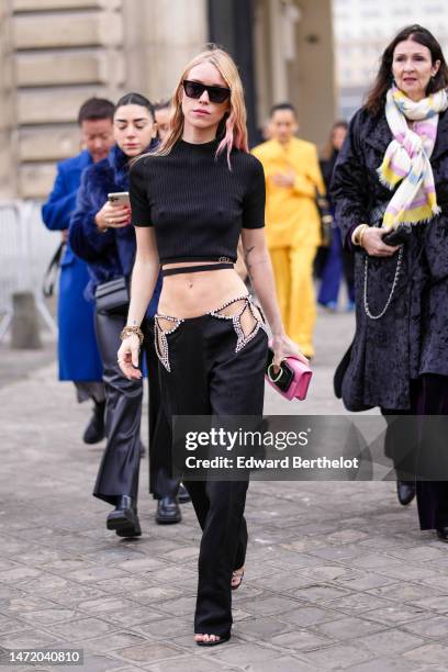 Guest wears black sunglasses, a black high neck / short sleeves / laces waist cropped top, black with cut-out waist embroidered rhinestones suit...