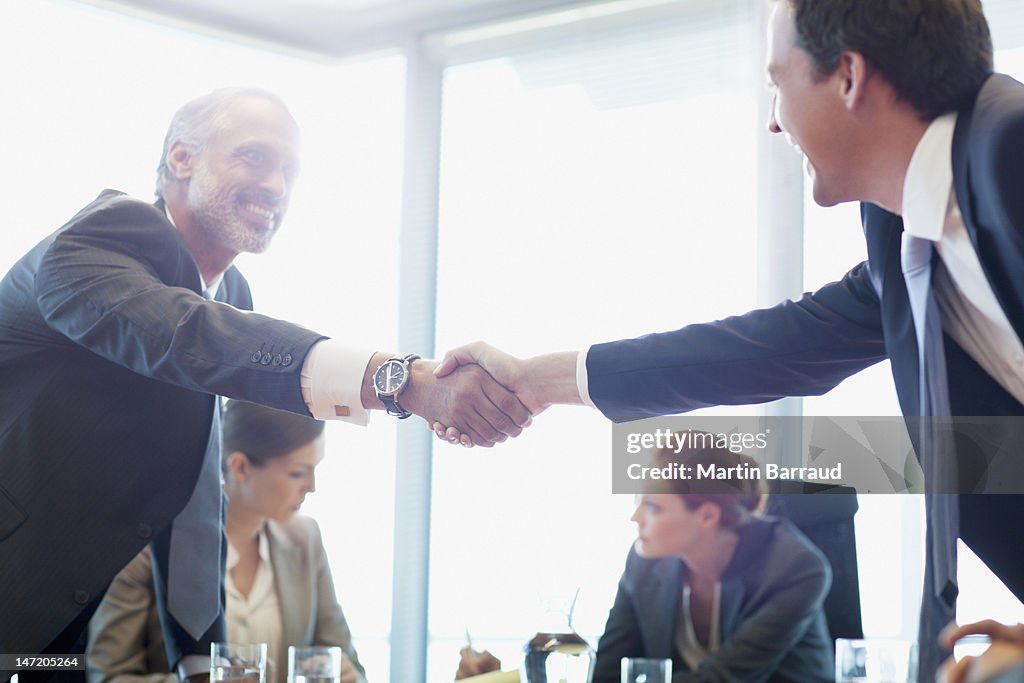 Businessmen shaking hands in conference room