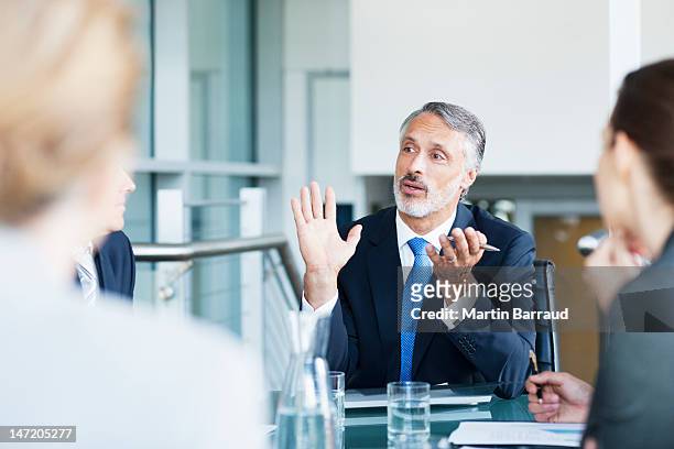 gesturing businessman leading meeting in conference room - differential focus stock pictures, royalty-free photos & images