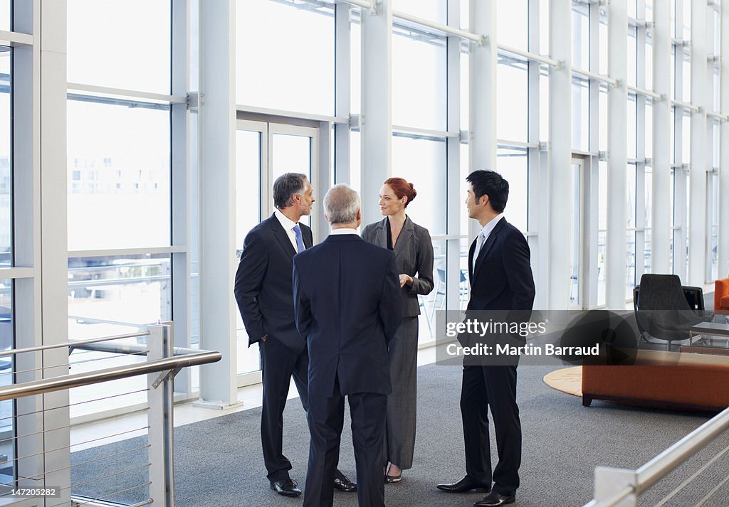 Business people meeting at window in office lobby