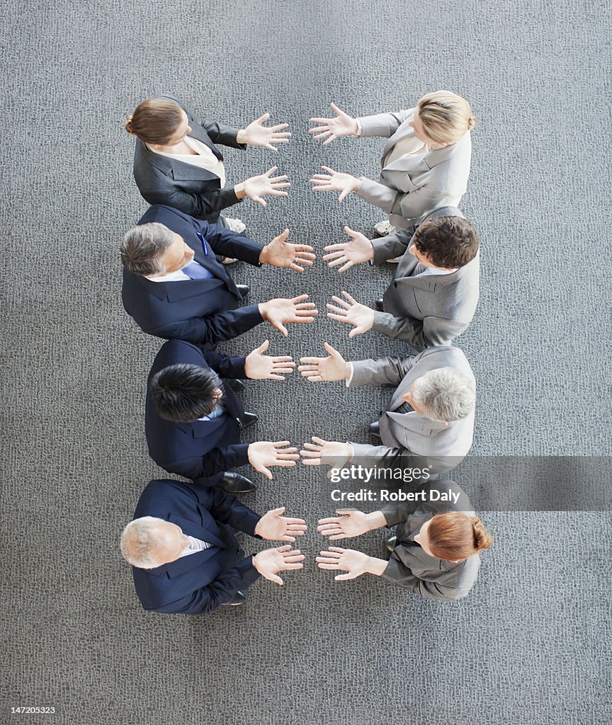Business people standing in row with palms up