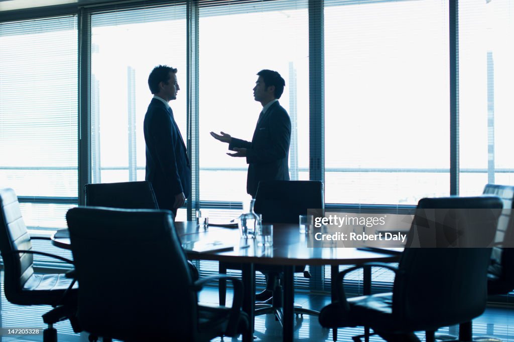 Businessmen talking face to face in conference room