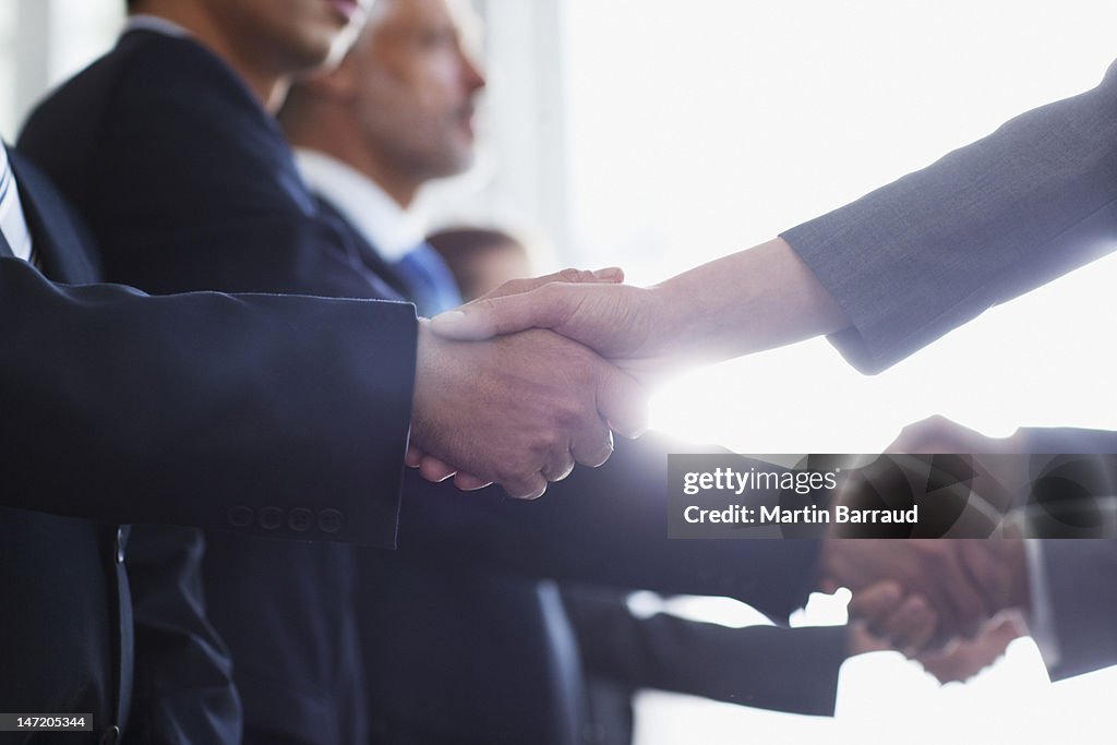 Close up of business people shaking hands in a row