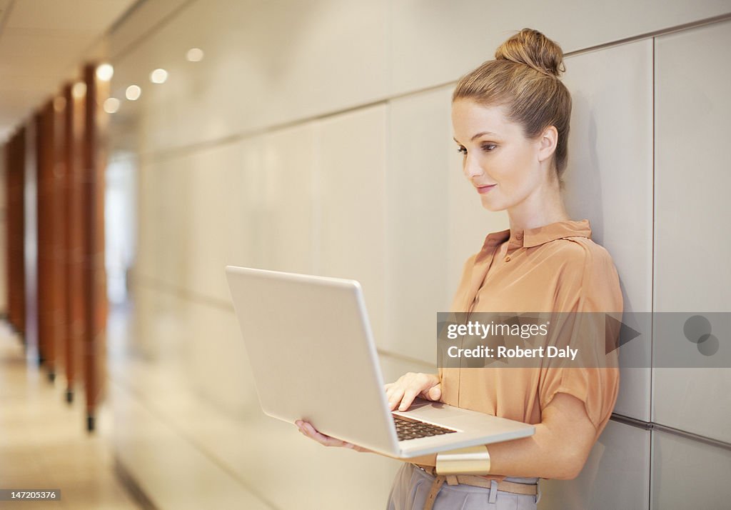 Businesswoman using laptop in corridor