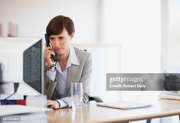 businesswoman talking on telephone and working at computer in office - answering email stock pictures, royalty-free photos & images