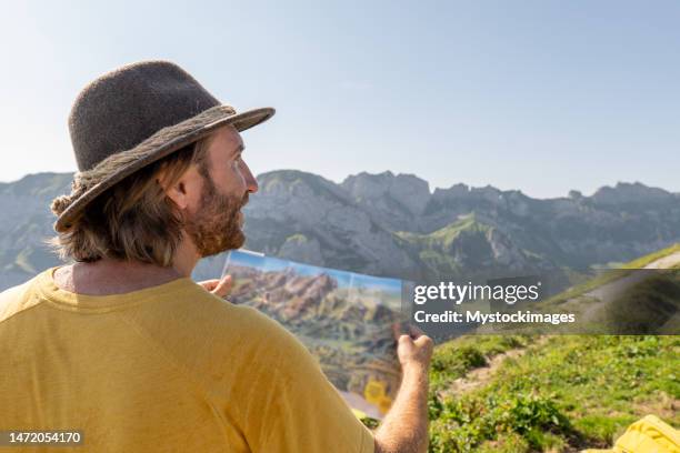 male hiker reads trail map in the swiss alps, people outdoor activities summer concept - appenzell innerrhoden stock pictures, royalty-free photos & images