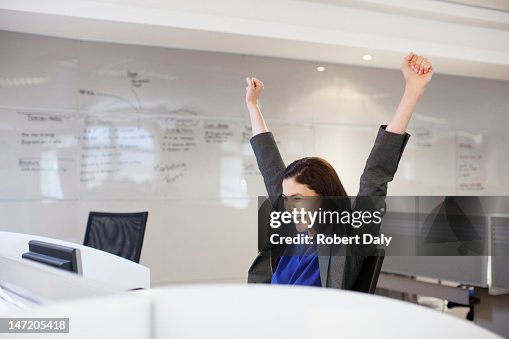 Enthusiastic businesswoman with arms raised in office Enthusiastic businesswoman with arms raised in office