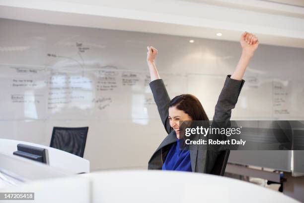 enthusiastic businesswoman with arms raised in office - work success stock pictures, royalty-free photos & images