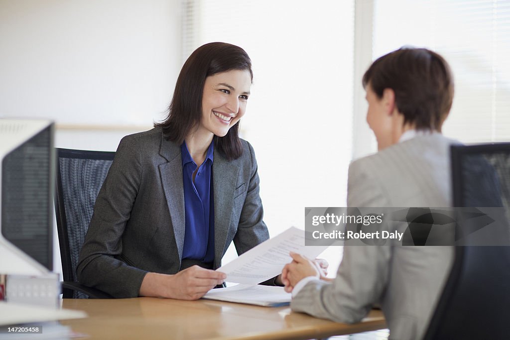 Businesswomen with paperwork talking face to face