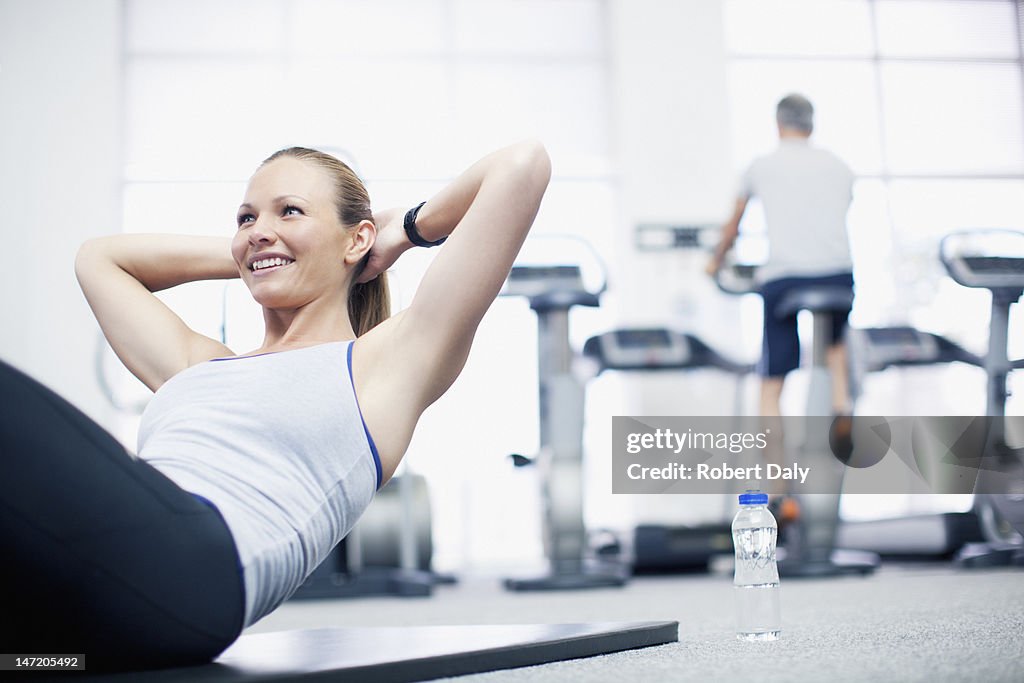 Smiling woman doing sit-ups in gymnasium