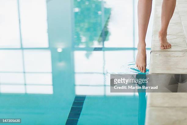 woman dipping toe in swimming pool - dip stockfoto's en -beelden
