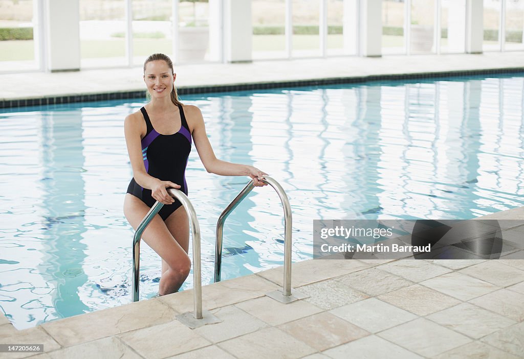 Porträt eines lächelnden Frau stehend auf Leiter im Swimmingpool