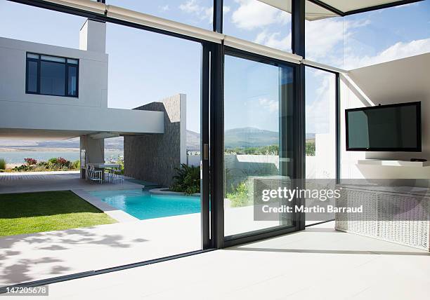 vista del patio e della piscina attraverso porte scorrevoli di moderno - porta foto e immagini stock