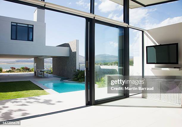 view of patio and swimming pool through sliding doors of modern house - patio doors bildbanksfoton och bilder