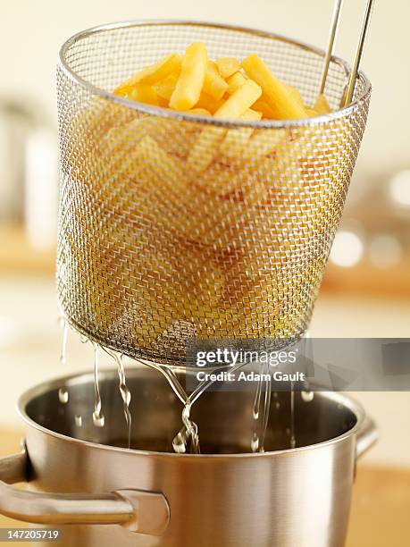 basket of french fries being removed from deep fryer - fast food french fries stock pictures, royalty-free photos & images