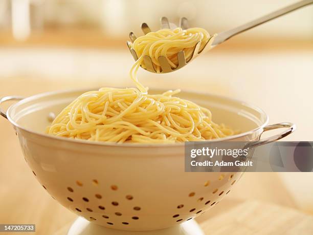 close up of spoon scooping spaghetti in colander - spaghetti stock-fotos und bilder