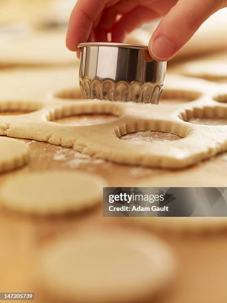 hand holding cookie cutter over dough - biscuit au sucre photos et images de collection