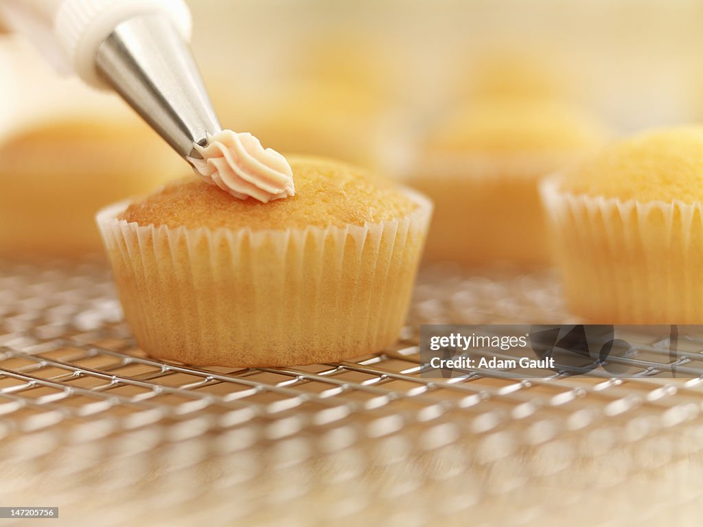 Close up of cupcakes being frosted