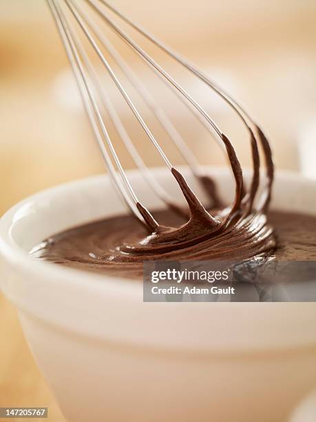 close up of wire whisk dipping in bowl of melted chocolate - schneebesen stock-fotos und bilder