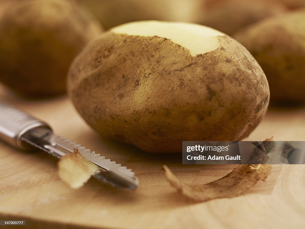 Close up of potato and peeler on cutting board