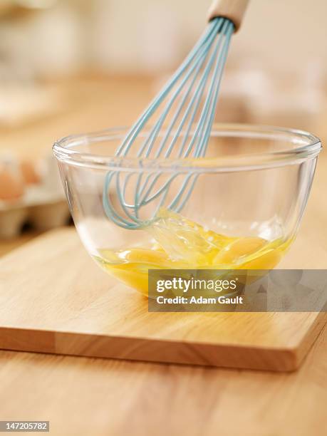 wire whisk beating eggs in bowl on cutting board - wire whisk ストックフォトと画像