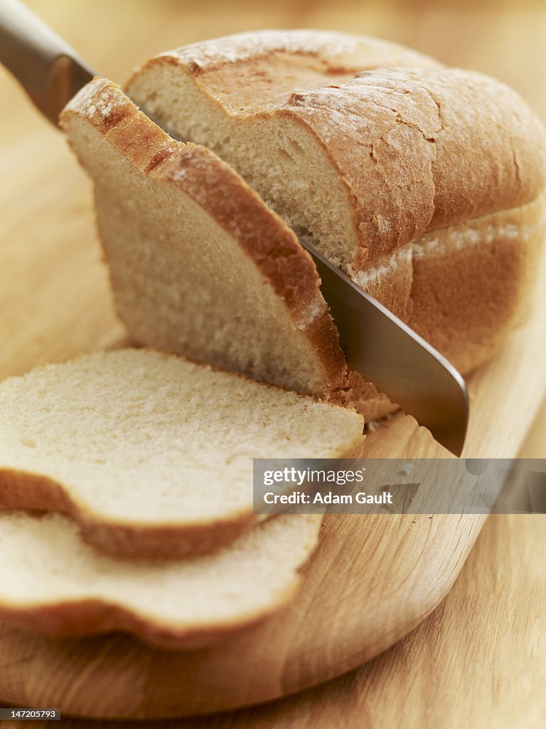 Knife slicing loaf of bread