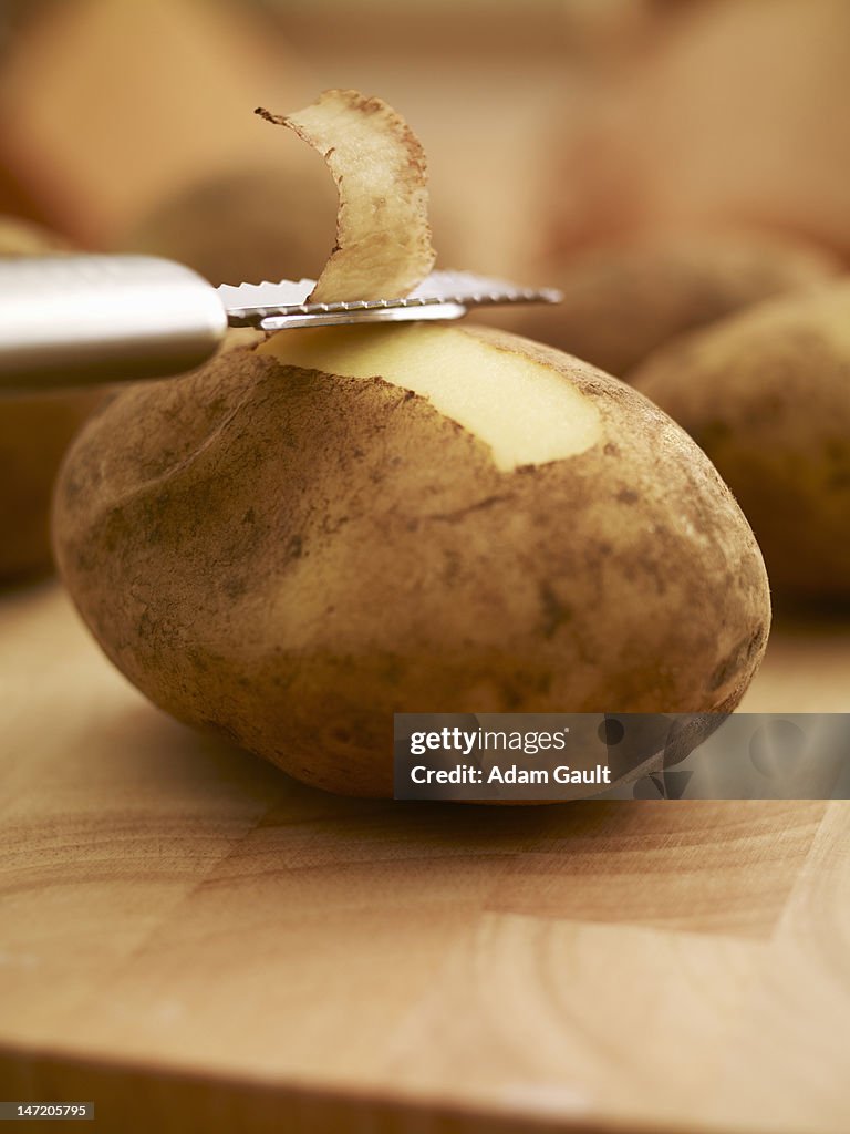 Peeler removing skin from potato