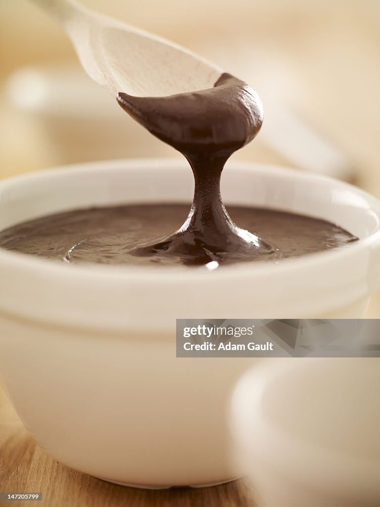 Spoon scooping melted chocolate from bowl