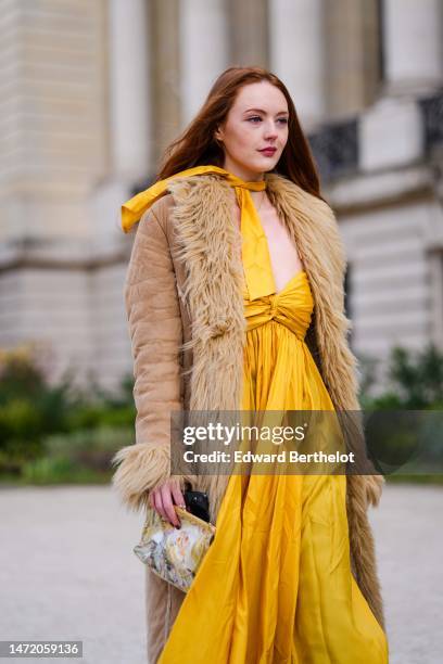 Guest wears a yellow small knot scarf, a matching yellow shoulder-off long dress, a brown suede with beige fur borders long coat, brown shiny leather...