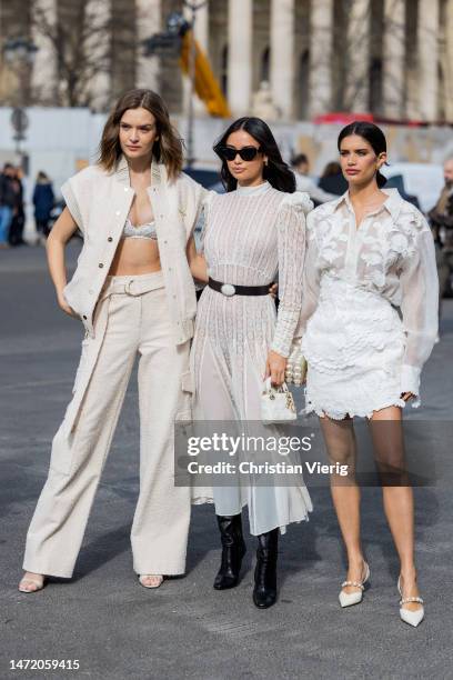 Josephine Skriver wears sleeveless jacket, bra, pants & Kelsey Merrit wears white laced belted dress, black boots & Sara Sampaio wears white...