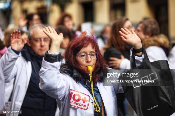 Woman dressed in a white coat raises her arms during a demonstration by primary care doctors and pediatricians in the center of Madrid on March 8 in...